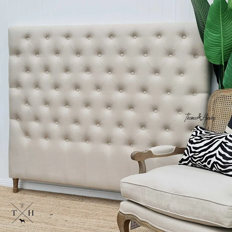 Hamptons style bed head with button tufting and neutral upholstery in a coastal bedroom